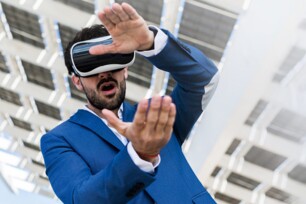 Mann mit VR-Brille auf dem Kopf zeigt etwas mit seinen Händen