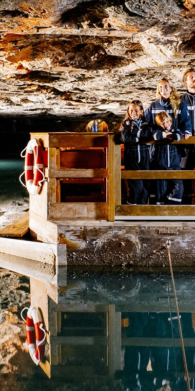 Eine Gruppe von Menschen, die auf einem Floß stehen und durch eine faszinierende Höhle auf einem See fahren.