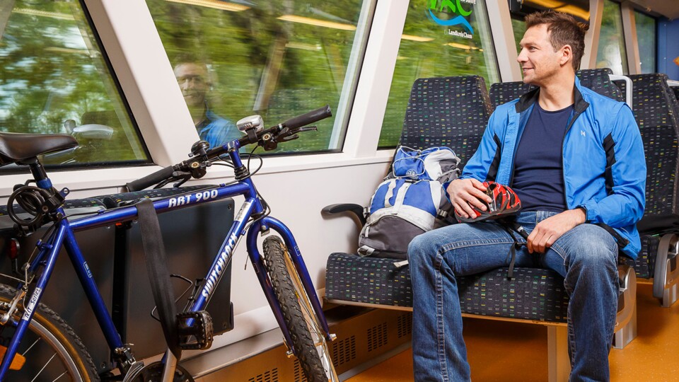 Mann sitzt mit seinem Fahrrad in der Bahn