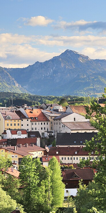 Blick über die Stadt Traunstein. Der Kirchturm ragt über die Häuser. Dahinter ist eine wunderschöne Berglandschaft.